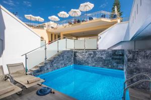 a swimming pool with two chairs and a balcony at Alexander House Hotel in Agia Pelagia