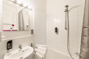 ein weißes Bad mit einer Dusche und einem Waschbecken in der Unterkunft Alecsa Hotel am Olympiastadion in Berlin