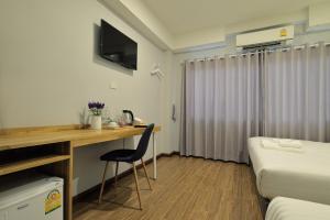a hotel room with a desk and a bed and a bed and a desk at De Lavender Bangkok Hotel in Bangkok