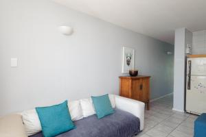 uma sala de estar com um sofá branco com almofadas azuis em Chakas Cove 101 em Ballito