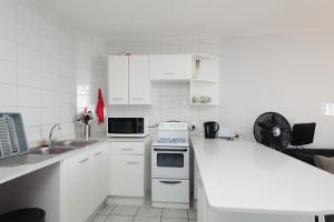 uma cozinha branca com um lavatório e um fogão em Chakas Cove 101 em Ballito