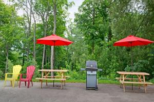 a grill and tables with chairs and red umbrellas at Knights Inn - Park Villa Motel, Midland in Midland