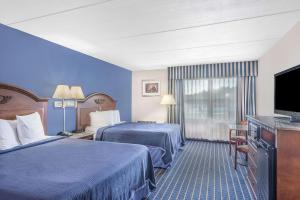 a hotel room with two beds and a flat screen tv at Howard Johnson by Wyndham Bangor in Bangor