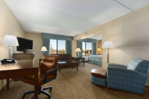 a hotel room with a desk and a bedroom at Wingate by Wyndham, Fayetteville NC in Fayetteville