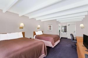 um quarto de hotel com duas camas e uma televisão de ecrã plano em Howard Johnson by Wyndham Vero Beach / Downtown em Vero Beach