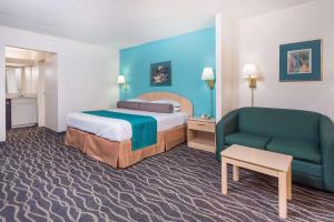 a hotel room with a bed and a green couch at Howard Johnson by Wyndham Commerce GA in Commerce