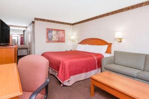 a hotel room with a red bed and chairs at Travelodge by Wyndham Chattanooga/Hamilton Place in Chattanooga