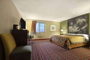 a hotel room with a bed and a chair at Super 8 by Wyndham Homewood Birmingham Area in Birmingham