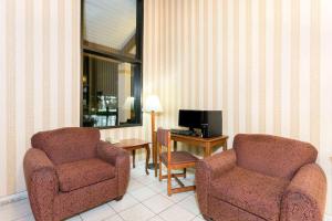 ein Wohnzimmer mit 2 Stühlen und einem TV in der Unterkunft Super 8 by Wyndham Riviera Beach West Palm Beach in Riviera Beach