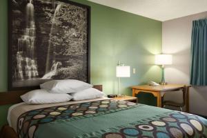 a hotel room with a bed and a painting on the wall at Super 8 by Wyndham Batesville in Batesville