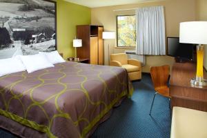 ein Hotelzimmer mit einem großen Bett und einem Stuhl in der Unterkunft Super 8 by Wyndham St. Clairsville OH/Wheeling WV Area in Saint Clairsville