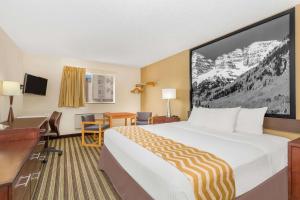 a hotel room with a large bed and a desk at Travelodge by Wyndham Loveland/Fort Collins Area in Loveland