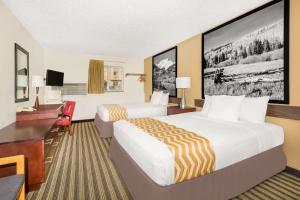 Habitación de hotel con 2 camas y escritorio en Travelodge by Wyndham Loveland/Fort Collins Area, en Loveland