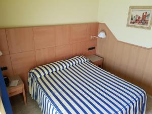 a bedroom with a bed with a blue and white stripes at Hostal Milenium in Els Monjos