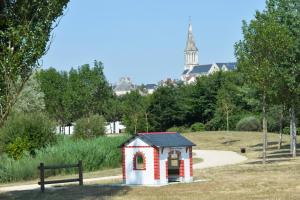 Logis de l'Hermitage في Le Louroux-Béconnais: منزل صغير للكلب الأحمر والبيض في الحديقة