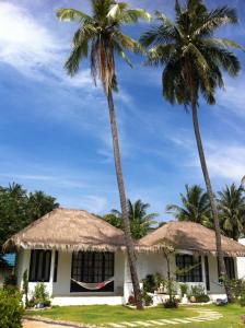 two palm trees in front of a house at Laemsing Whitehouse Resort in Laem Sing