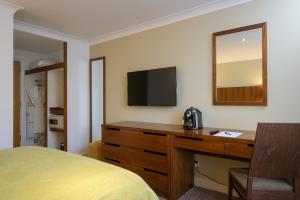 um quarto de hotel com uma cama e uma secretária com uma televisão em The Woodlands Event Centre em Wyboston