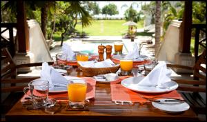 a wooden table with plates and glasses of orange juice at Avillion Villa Cinta @Sanur, Bali in Sanur