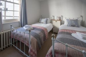 two twin beds in a room with a window at Pugwash in Aldeburgh