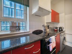 a kitchen with red cabinets and a stove top oven at LSE Bankside House in London