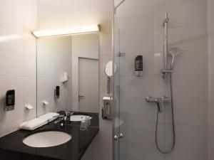 uma casa de banho com um lavatório e um chuveiro em Arion Airport Hotel em Schwechat