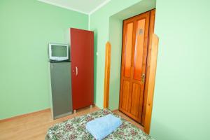 a room with a bed and a tv and a door at Pilgrim Hostel in Ivano-Frankivsk