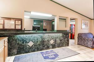 a hotel lobby with a reception desk and a chair at Knights Inn Farmington Hills in Farmington Hills