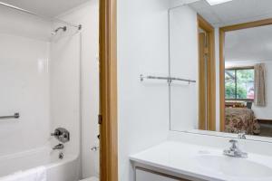 Knights Inn Pittston في Pittston: حمام مع حوض ومرآة وحوض استحمام