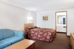 a hotel room with a bed and a blue couch at Knights Inn Pittston in Pittston
