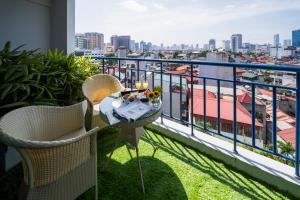 balcón con mesa, sillas y vistas a la ciudad en Rose Garden Residences en Hanói