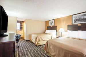 a hotel room with two beds and a flat screen tv at Travelodge by Wyndham South Burlington in Burlington