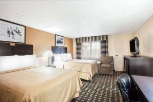 a hotel room with two beds and a television at Travelodge by Wyndham South Burlington in Burlington