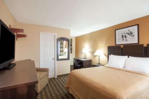 a hotel room with a bed and a flat screen tv at Travelodge by Wyndham South Burlington in Burlington +5 photos