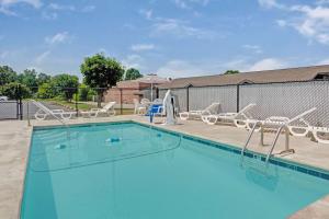 a swimming pool with chairs and an umbrella at Super 8 by Wyndham Shelby in Shelby