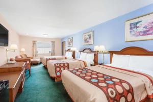 a hotel room with two beds and a television at Super 8 by Wyndham Greensboro in Greensboro