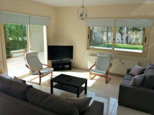a living room with a couch and chairs and a tv at ANTHORINA VILLA 9 in Protaras