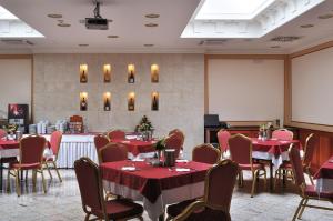 a dining room with tables and chairs with red table cloth at Hotel Ködmön in Eger