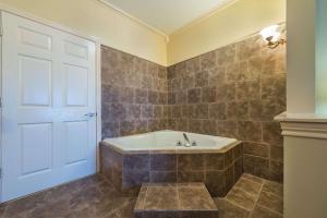 a bathroom with a tub and a white door at Super 8 by Wyndham Greenville in Greenville