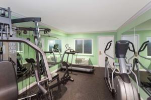 a gym with green walls and tread machines at Travelodge by Wyndham Orange County Airport/ Costa Mesa in Costa Mesa