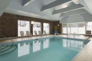 a large swimming pool with chairs and tables at Travelodge Hotel by Wyndham Vancouver Airport in Richmond