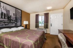ein Hotelzimmer mit einem Bett und einem Schreibtisch in der Unterkunft Super 8 by Wyndham Indianapolis/NE/Castleton Area in Indianapolis