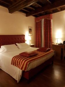 a bedroom with a large bed with white sheets and red curtains at Domus Julia in Rome