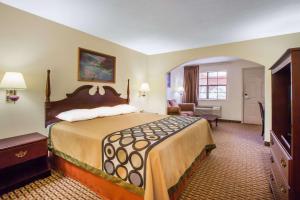 a hotel room with a large bed and a chair at Super 8 by Wyndham Cabot in Cabot