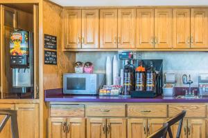 a kitchen with wooden cabinets and a counter with a microwave at Super 8 by Wyndham West Middlesex/Sharon Area in West Middlesex