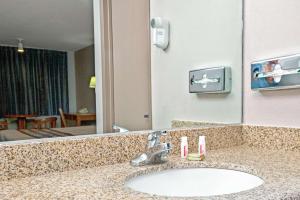 La salle de bains est pourvue d'un lavabo et d'un grand miroir. dans l'établissement Super 8 by Wyndham Upland Ontario CA, à Upland