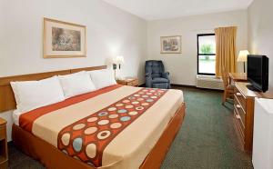 a hotel room with a large bed and a television at Super 8 by Wyndham Hampshire IL in Hampshire