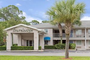 a vacation house with a palm tree in front of it at Travelodge Suites by Wyndham MacClenny I-10 in Macclenny