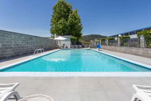 a swimming pool with two chairs at Travelodge by Wyndham Grants Pass in Grants Pass