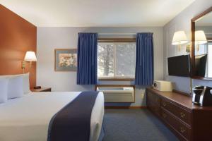 a hotel room with a bed and a window at Travelodge by Wyndham Motel of St Cloud in Saint Cloud +18 photos