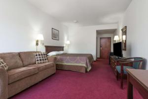 ein Hotelzimmer mit einem Sofa und einem Bett in der Unterkunft Super 8 by Wyndham Grayson in Grayson